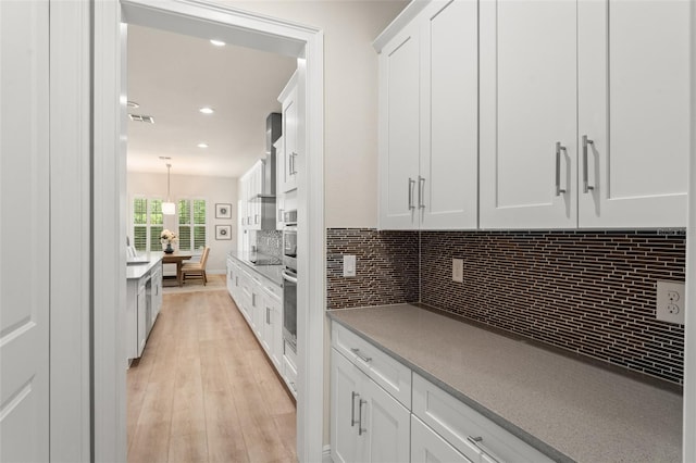 8017 Chilton Dr, Orlando, FL 32836 - kitchen featuring oven, white cabinets, light wood-style floors, backsplash, and recessed lighting