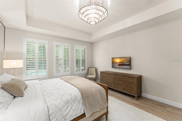 8017 Chilton Dr, Orlando, FL 32836 - bedroom featuring baseboards, wood finished floors, a chandelier, and a tray ceiling