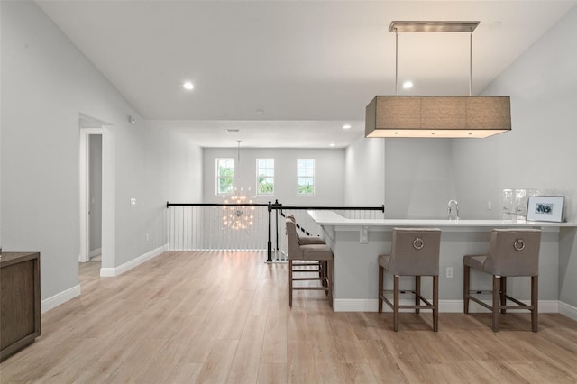 8017 Chilton Dr, Orlando, FL 32836 - kitchen with a chandelier, a kitchen bar, light wood-style flooring, a peninsula, and baseboards