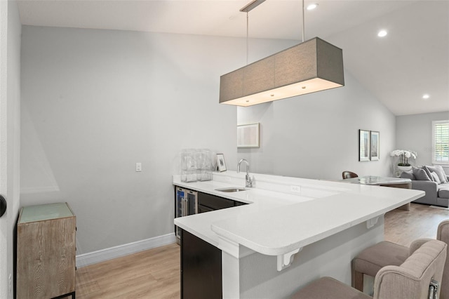 8017 Chilton Dr, Orlando, FL 32836 - kitchen with light wood finished floors, a sink, a kitchen bar, wine cooler, and a peninsula