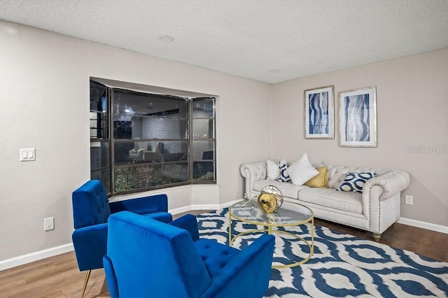 living room with a textured ceiling, wood finished floors, and baseboards