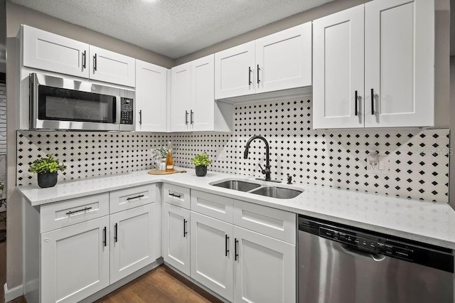 kitchen with a sink, tasteful backsplash, white cabinetry, a textured ceiling, and appliances with stainless steel finishes