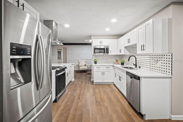 kitchen with white cabinetry, stainless steel appliances, light countertops, and a sink
