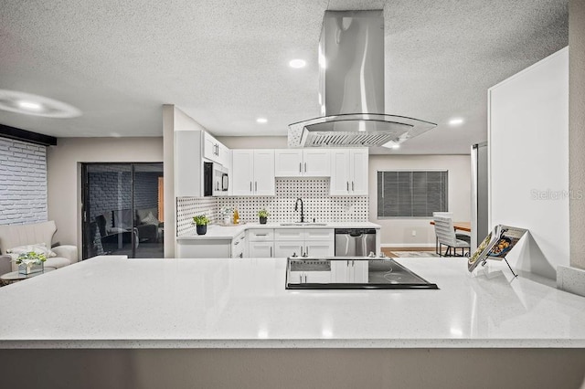 kitchen featuring island range hood, appliances with stainless steel finishes, a sink, white cabinetry, and a textured ceiling