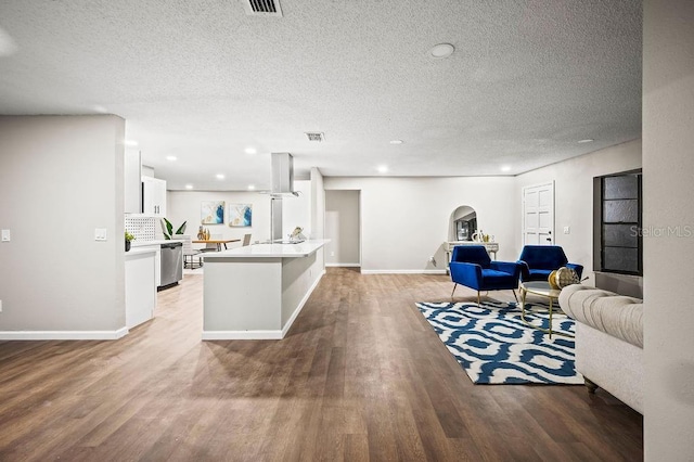 living room with a textured ceiling, visible vents, baseboards, arched walkways, and light wood-type flooring
