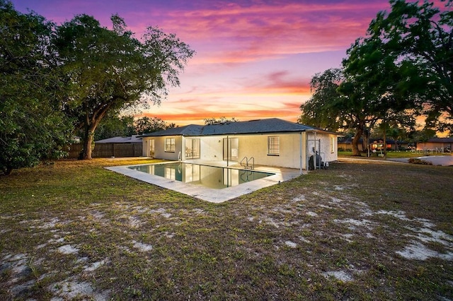 rear view of property with an outdoor pool, stucco siding, a patio area, and fence