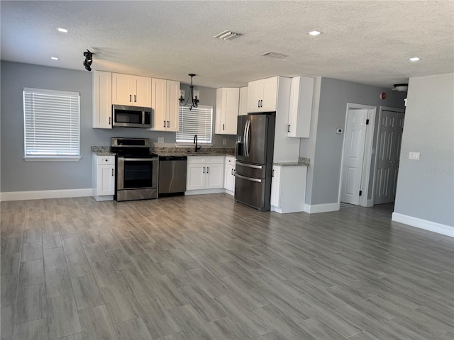 3735 Alabama Ave NE, Saint Petersburg, FL 33703 - kitchen featuring white cabinetry, stainless steel appliances, stone counters, baseboards, and a textured ceiling
