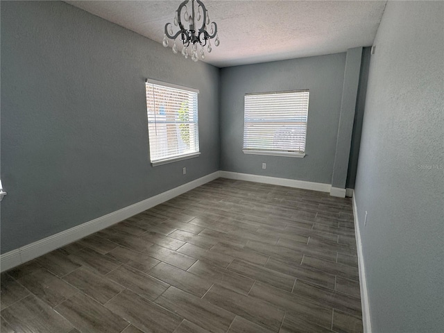 3735 Alabama Ave NE, Saint Petersburg, FL 33703 - spare room with a chandelier, dark wood-type flooring, a textured wall, baseboards, and a textured ceiling