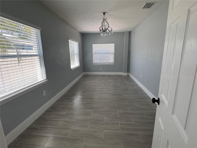 3735 Alabama Ave NE, Saint Petersburg, FL 33703 - unfurnished room featuring a chandelier, visible vents, baseboards, wood finish floors, and a textured ceiling