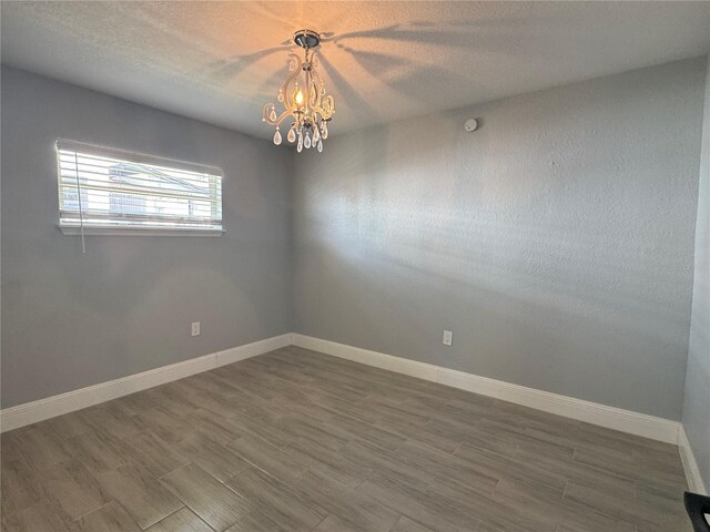 3735 Alabama Ave NE, Saint Petersburg, FL 33703 - spare room featuring a textured ceiling, wood finished floors, a notable chandelier, and baseboards