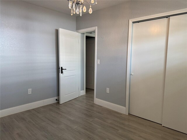 3735 Alabama Ave NE, Saint Petersburg, FL 33703 - unfurnished bedroom featuring an inviting chandelier, wood finished floors, baseboards, and a closet