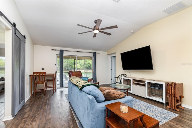 living room with ceiling fan, visible vents, vaulted ceiling, a barn door, and dark wood-style floors