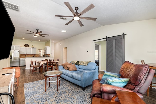 living area featuring ceiling fan, dark wood finished floors, a barn door, and visible vents