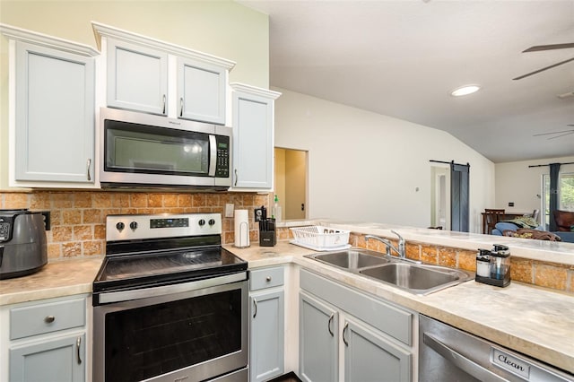 kitchen featuring a sink, appliances with stainless steel finishes, tasteful backsplash, and vaulted ceiling