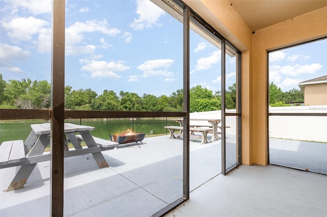 unfurnished sunroom with a healthy amount of sunlight, concrete flooring, and an outdoor fire pit