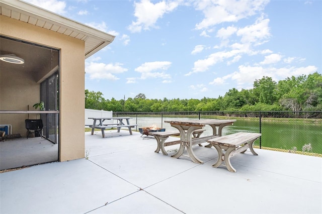 view of patio featuring outdoor dining area, fence, and a forest view