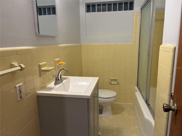 full bath with enclosed tub / shower combo, toilet, tile walls, vanity, and tile patterned flooring