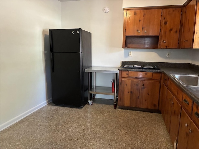 kitchen with baseboards, dark countertops, brown cabinets, and freestanding refrigerator