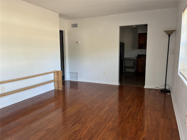 spare room featuring visible vents, baseboards, and dark wood-type flooring