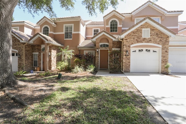 7613 Bay Port Rd Unit 34, Orlando, FL 32819 - view of front facade with stucco siding, a garage, concrete driveway, and stone siding