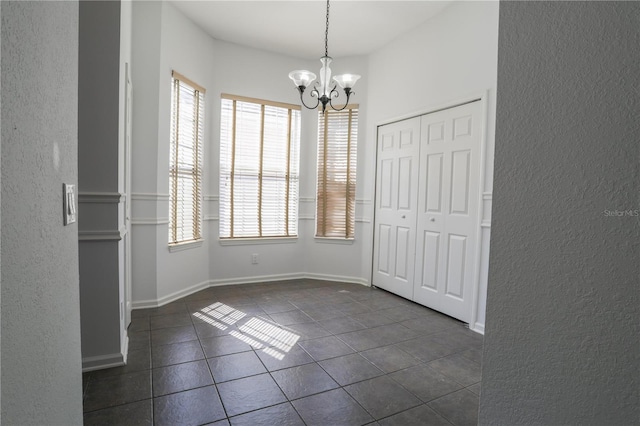 7613 Bay Port Rd Unit 34, Orlando, FL 32819 - unfurnished dining area featuring dark tile patterned flooring, an inviting chandelier, a textured wall, and a healthy amount of sunlight