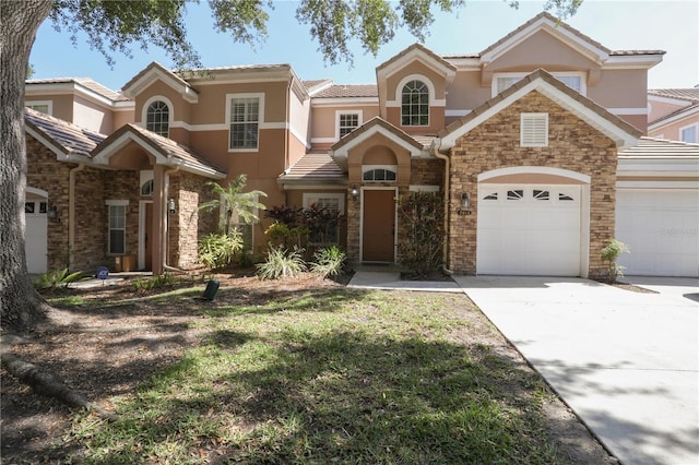 7613 Bay Port Rd Unit 34, Orlando, FL 32819 - view of front of property featuring driveway, stone siding, a tiled roof, an attached garage, and stucco siding