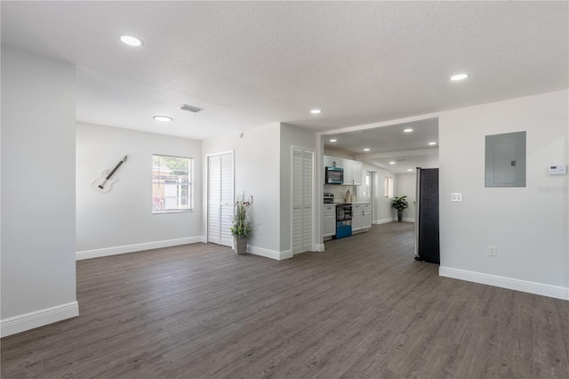 unfurnished living room featuring dark wood-type flooring, electric panel, recessed lighting, and visible vents