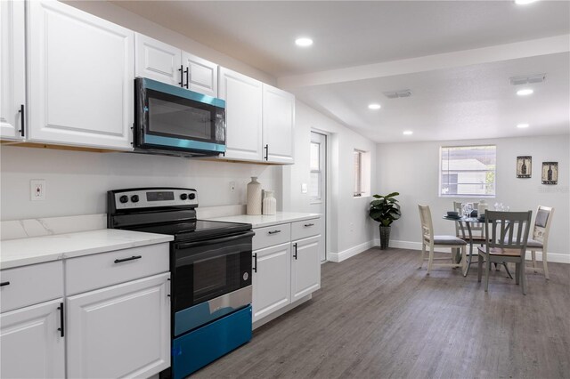 kitchen with baseboards, visible vents, white cabinetry, wood finished floors, and appliances with stainless steel finishes