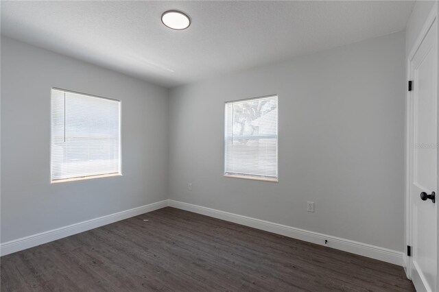 empty room featuring dark wood-type flooring and baseboards