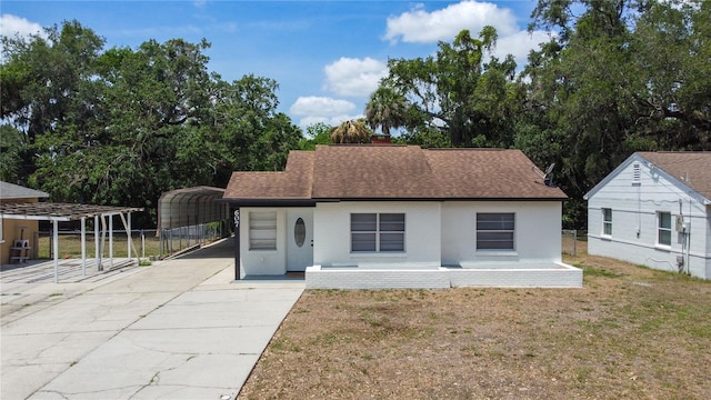 view of front facade featuring roof with shingles, a front lawn, a carport, driveway, and brick siding
