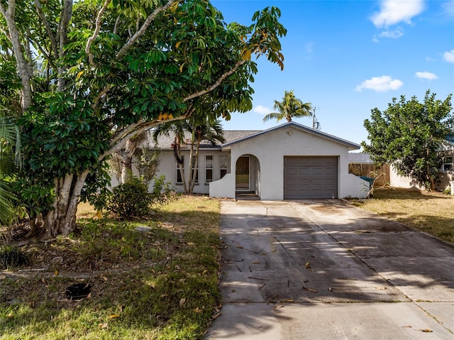single story home featuring a garage, driveway, fence, and stucco siding