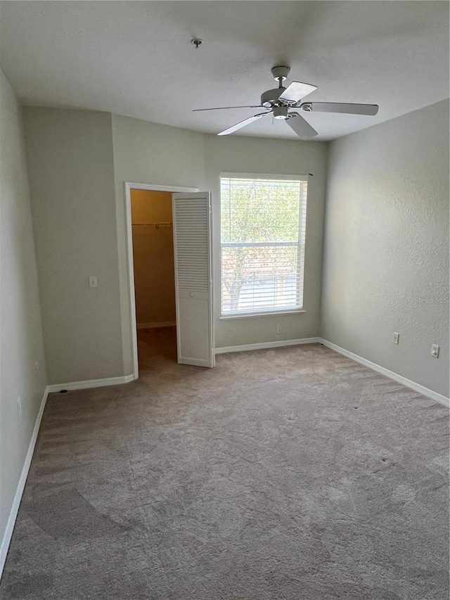 carpeted spare room with a ceiling fan, baseboards, and fire sprinkler in ceiling