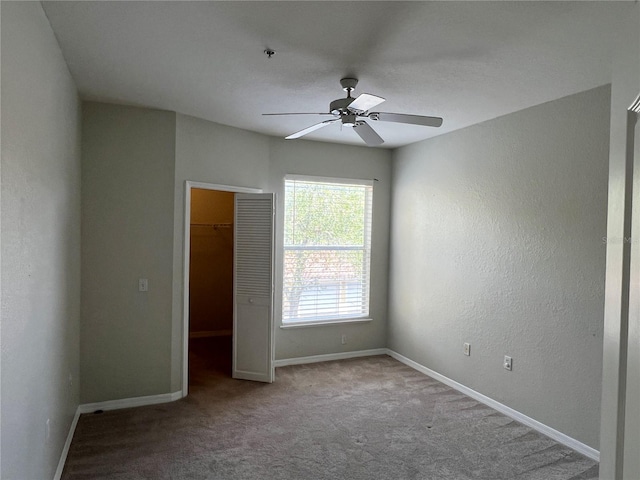 spare room featuring ceiling fan, carpet flooring, baseboards, and a textured wall