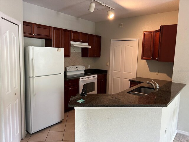 kitchen featuring white appliances, a sink, under cabinet range hood, a peninsula, and tasteful backsplash