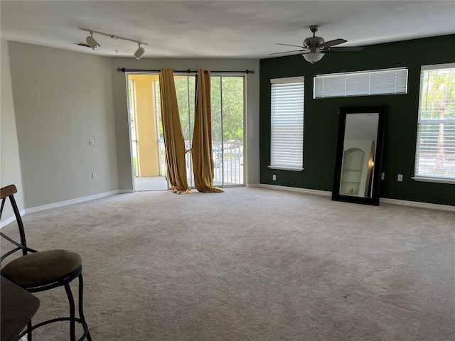 carpeted spare room featuring ceiling fan, plenty of natural light, and baseboards