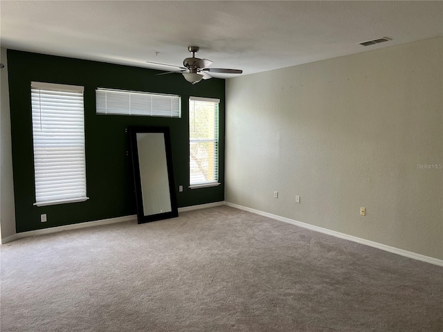 spare room featuring carpet, a ceiling fan, and baseboards
