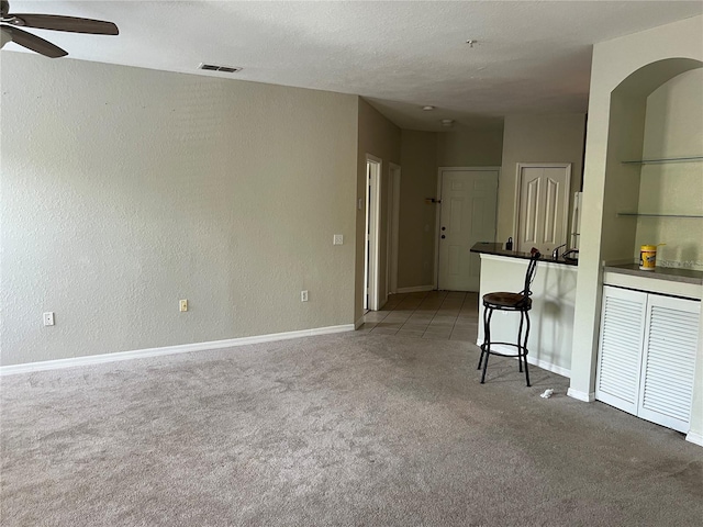 carpeted spare room featuring a ceiling fan and baseboards