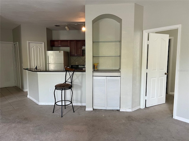 kitchen with freestanding refrigerator, dark countertops, carpet, and a peninsula