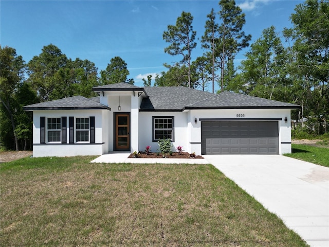 prairie-style house featuring concrete driveway, a front lawn, a shingled roof, an attached garage, and stucco siding