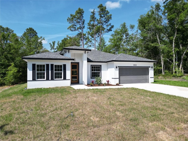 prairie-style house featuring an attached garage, concrete driveway, a front lawn, and stucco siding