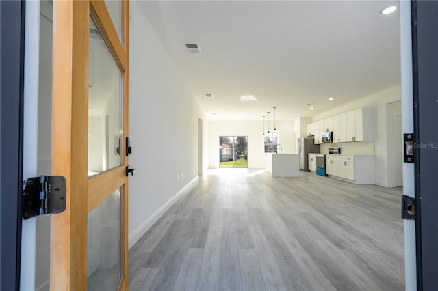 unfurnished living room featuring light wood-type flooring, baseboards, visible vents, and recessed lighting