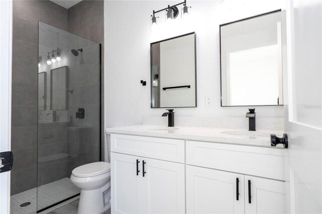 bathroom featuring toilet, a sink, double vanity, and a stall shower