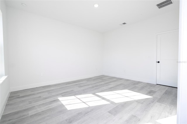 unfurnished room with light wood-type flooring, baseboards, visible vents, and recessed lighting