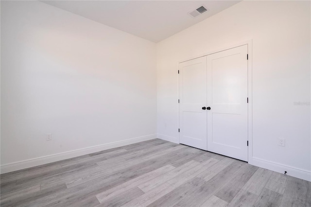 unfurnished bedroom with baseboards, light wood finished floors, visible vents, and a closet