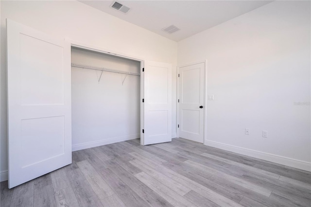 unfurnished bedroom featuring baseboards, a closet, visible vents, and light wood-style flooring
