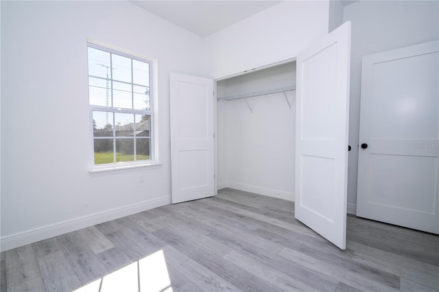 unfurnished bedroom with baseboards, wood finished floors, and a closet