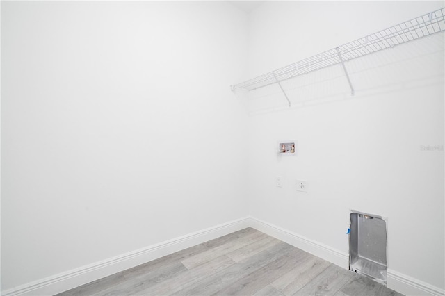 clothes washing area with wood finished floors, electric dryer hookup, baseboards, laundry area, and washer hookup
