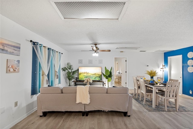 living room with a textured ceiling, visible vents, baseboards, a ceiling fan, and wood finished floors