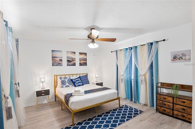 bedroom with a textured ceiling, light wood finished floors, and a ceiling fan