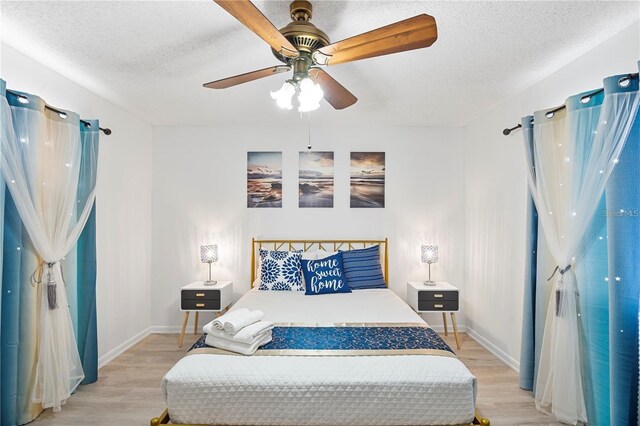 bedroom featuring baseboards, a textured ceiling, and light wood-style flooring